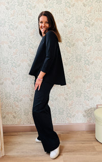 Completo composto da pantaloni con chiusura con zip e cerniera ed elastico sul retro. Taglio a palazzo. Felpa con scollo tondo dal taglio ampio e svasato.