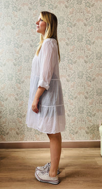 Abito bianco, 100% cotone, scollo a V con manica lunga con risvolto non cucito. Taglio svasato con balze leggere. Perfetto come copricostume. 