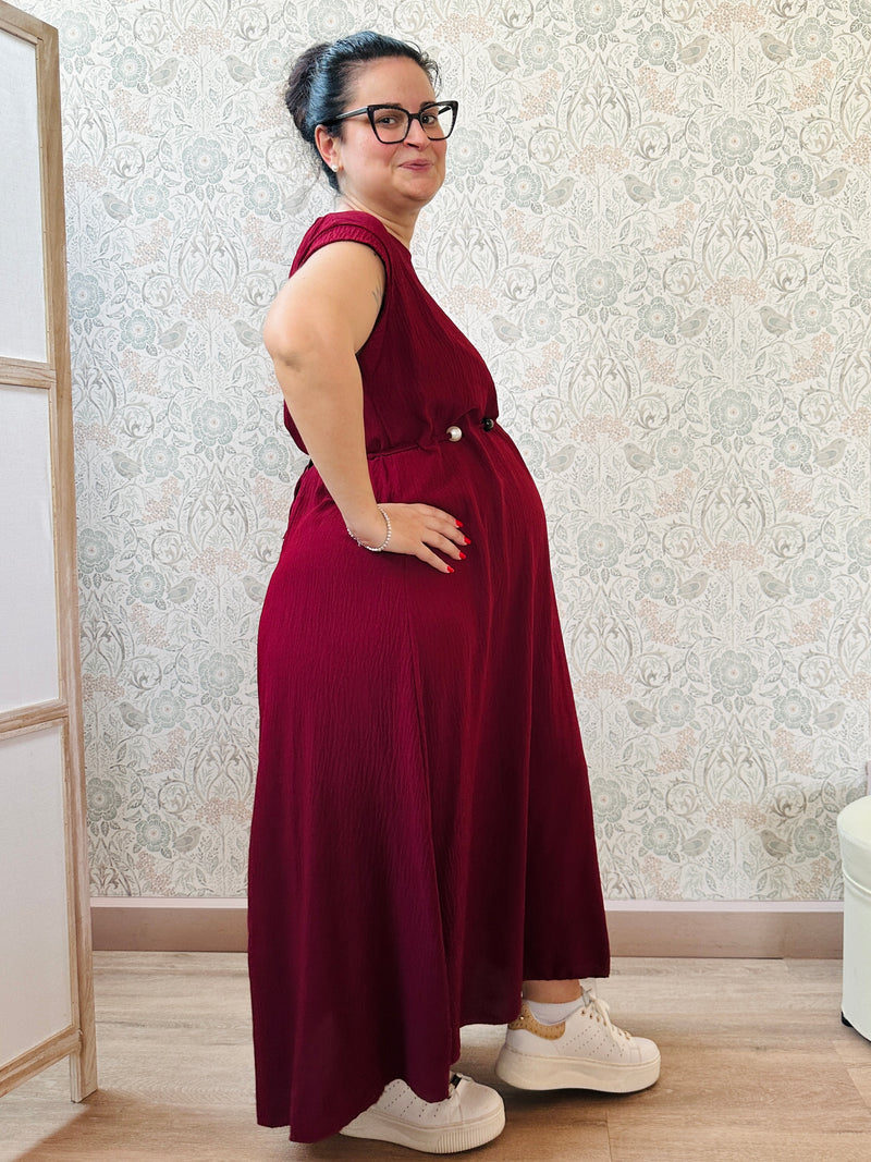 Abito lungo bordeaux con scollo tondo e manica corta. Cintura a nastro in vita regolabile con applicazioni. Vestibilità morbida e ampia. 