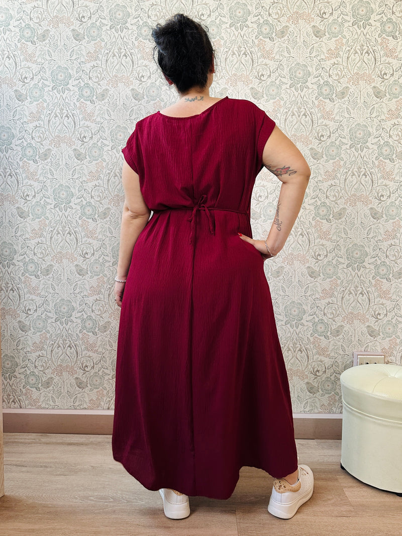 Abito lungo bordeaux con scollo tondo e manica corta. Cintura a nastro in vita regolabile con applicazioni. Vestibilità morbida e ampia. Retro