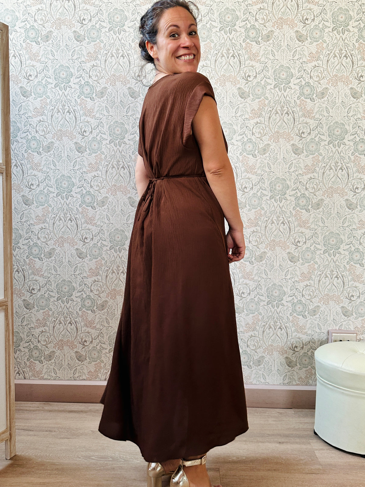 Abito lungo marrone con scollo tondo e manica corta. Cintura a nastro in vita regolabile con applicazioni. Vestibilità morbida e ampia. 
