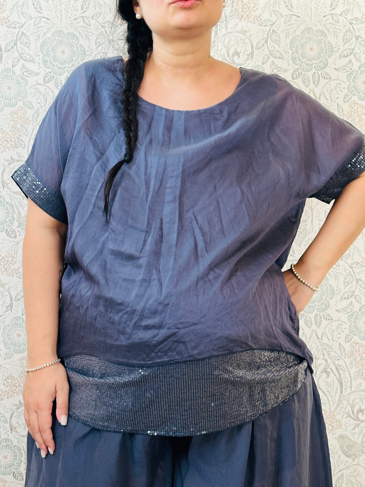 Blusa curvy a manica corta, scollo tondo profondo e top interno in fresca viscosa. Strass applicati sul bordo delle maniche e sul bordo finale del top. 