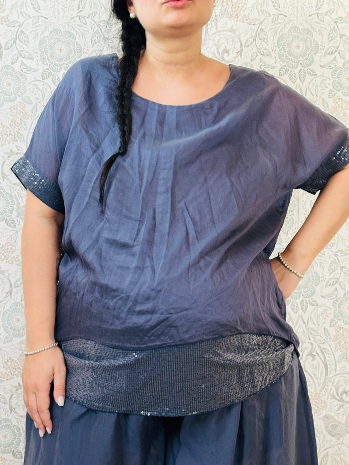 Blusa curvy a manica corta, scollo tondo profondo e top interno in fresca viscosa. Strass applicati sul bordo delle maniche e sul bordo finale del top. 