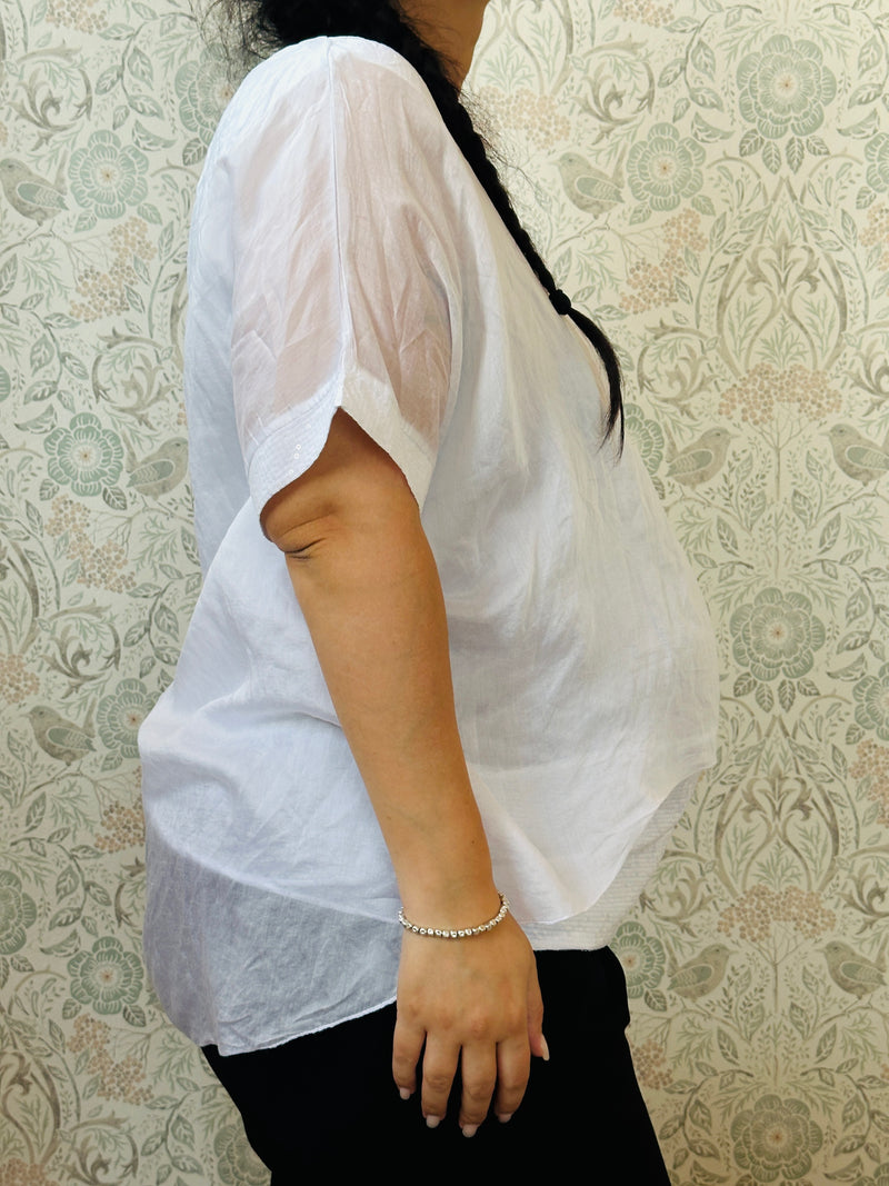 Blusa curvy a manica corta, scollo tondo profondo e top interno in fresca viscosa. Strass applicati sul bordo delle maniche e sul bordo finale del top. 