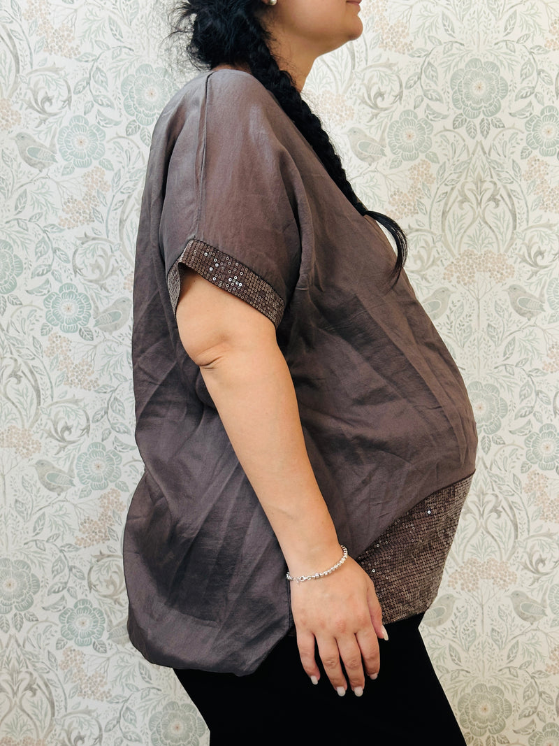 Blusa curvy a manica corta, scollo tondo profondo e top interno in fresca viscosa. Strass applicati sul bordo delle maniche e sul bordo finale del top. 