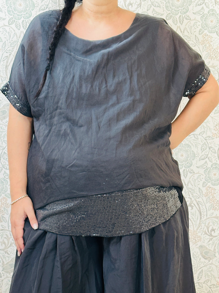Blusa curvy a manica corta, scollo tondo profondo e top interno in fresca viscosa. Strass applicati sul bordo delle maniche e sul bordo finale del top. 