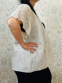 Blusa a manica corta con scollo tondo. Taglio svasato e ricami sangallo davanti. 