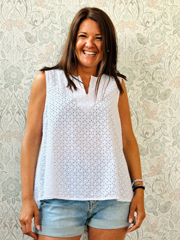 Blusa Bianca in cotone, in sangallo con dettaglio a v sullo scollo. Taglio svasato e leggero spacco sul retro.