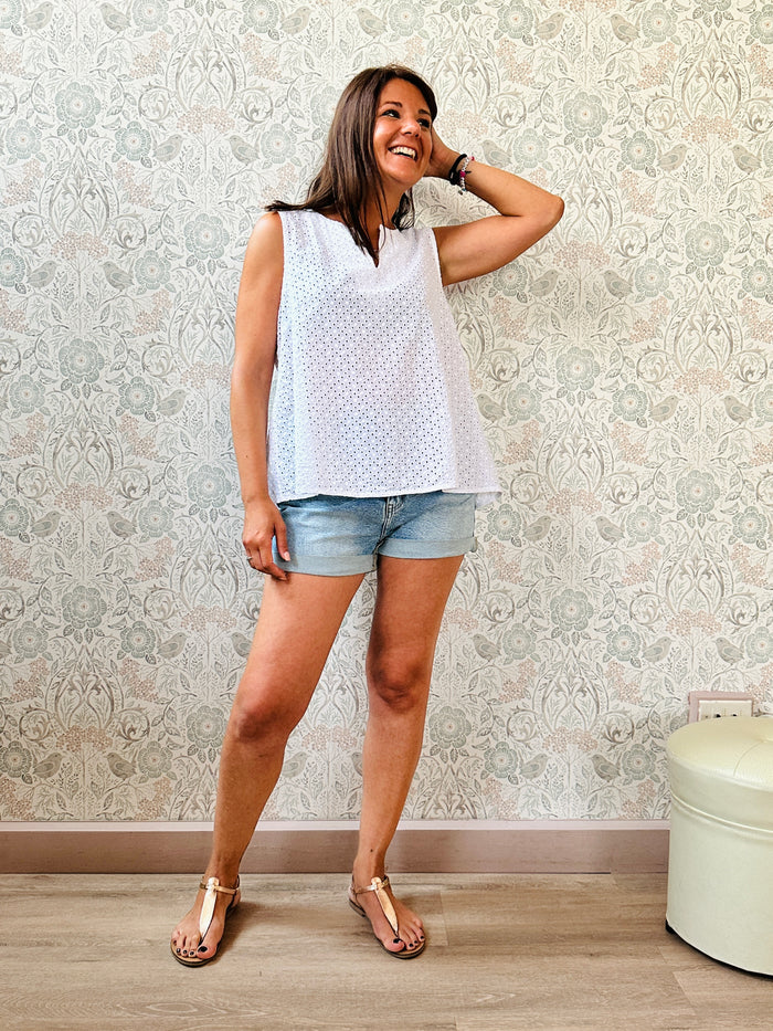 Blusa Bianca in cotone, in sangallo con dettaglio a v sullo scollo. Taglio svasato e leggero spacco sul retro.