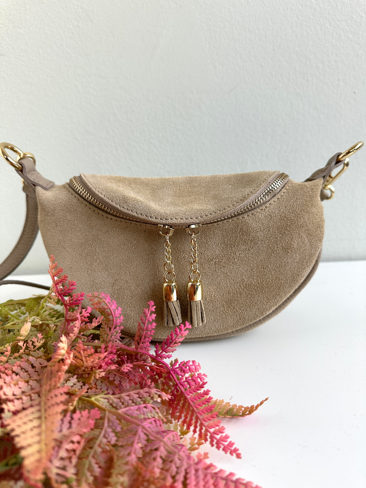 Borsa 100% pelle scamosciata a forma di mezzaluna. Chiusura con zip, tracolla regolabile e removibile. 