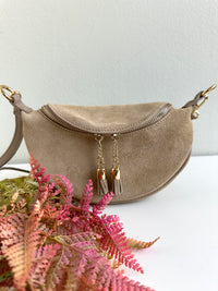 Borsa 100% pelle scamosciata a forma di mezzaluna. Chiusura con zip, tracolla regolabile e removibile. 