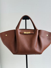 Borsa 100% pelle con manici a spalla, chiusura zip, tasca interna e tracolla regolabile. Colore marrone. 