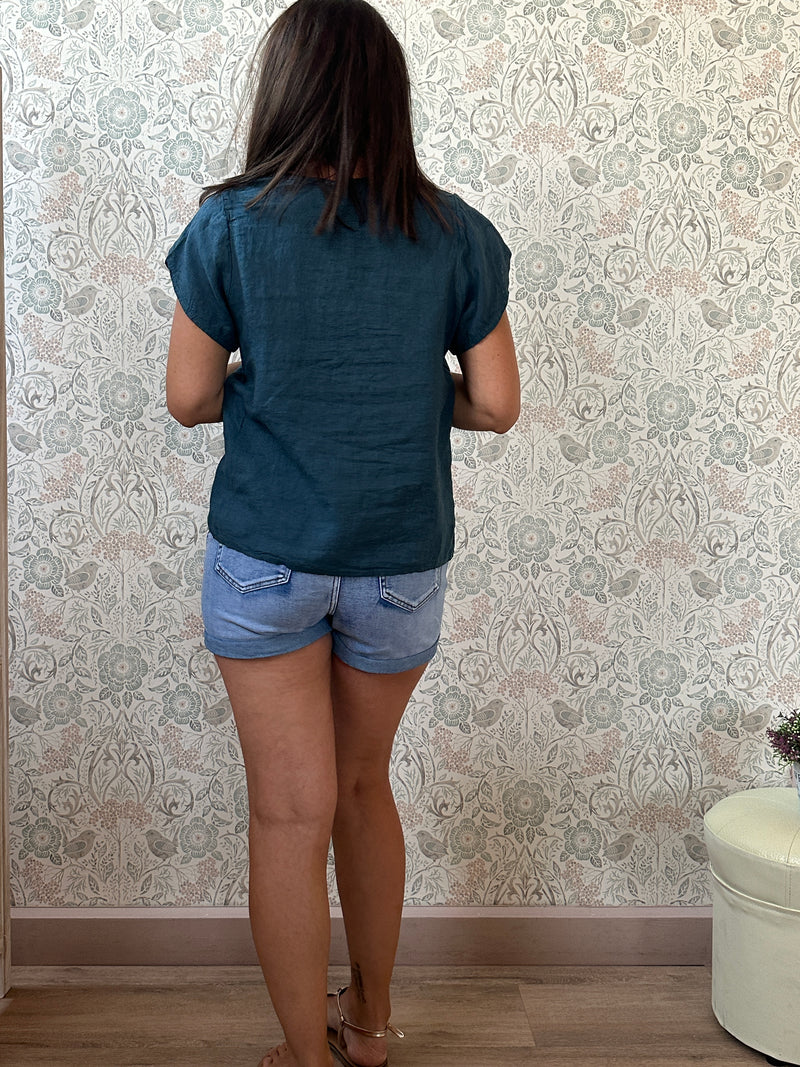 Camicia a manica corta con scollo a barchetta, colletto laterale e dettaglio linea con bottoni decorativi. 