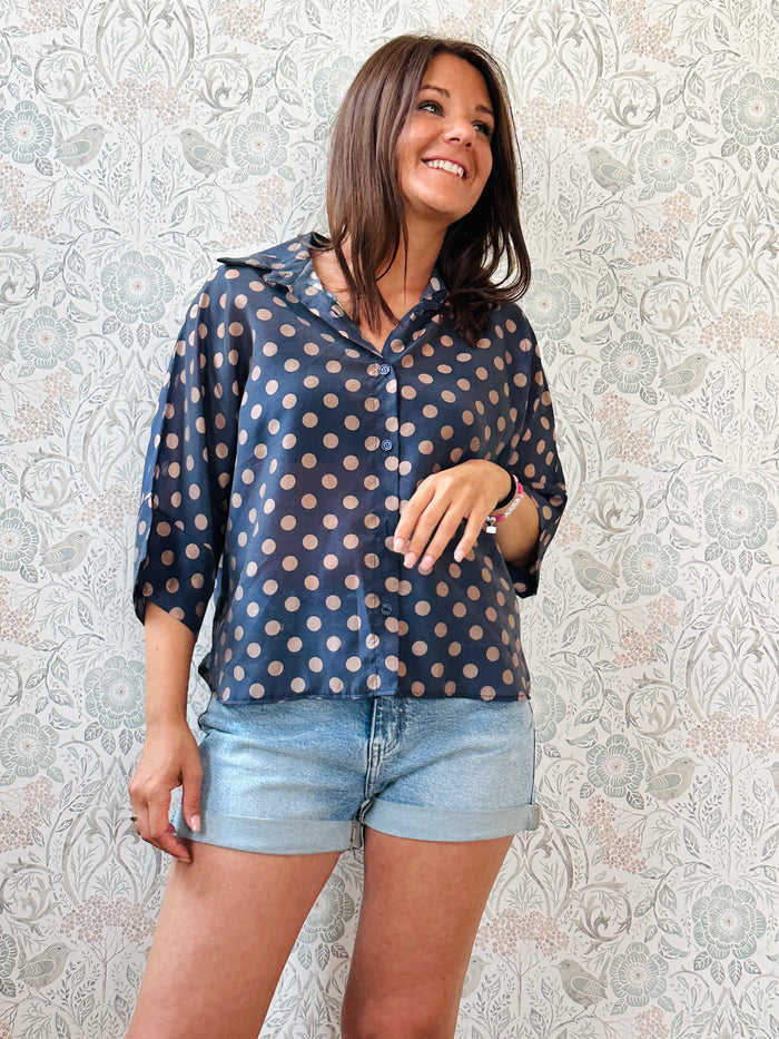Camicia fantasia blu con pois, con bottoni in chiusura e manica a pipistrello. 