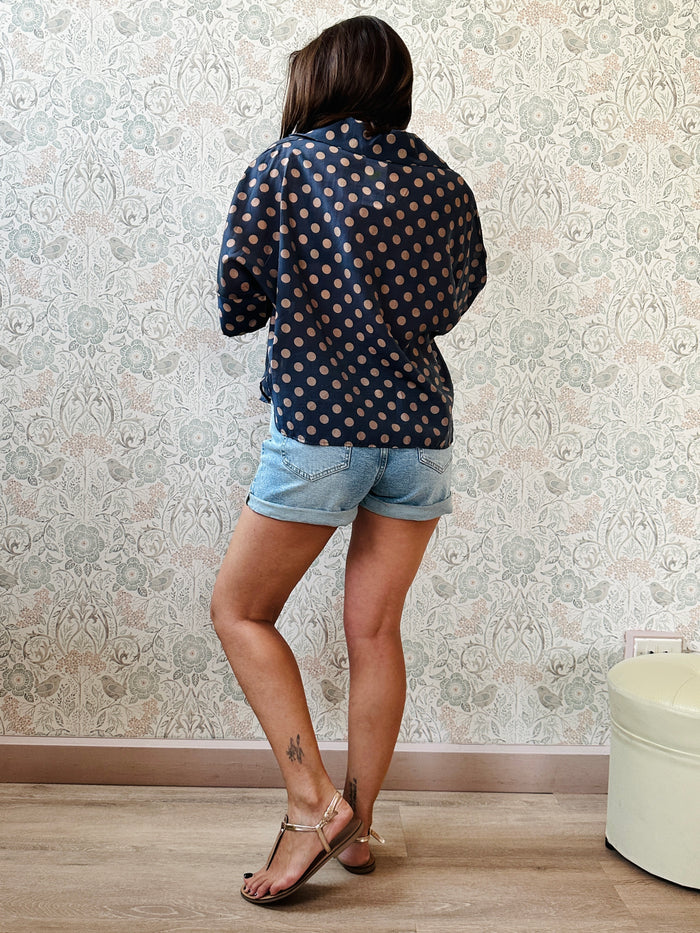 Camicia fantasia blu con pois, con bottoni in chiusura e manica a pipistrello. 