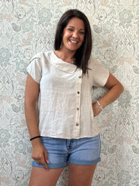 Camicia a manica corta con scollo a barchetta, colletto laterale e dettaglio linea con bottoni decorativi. 
