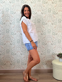 Camicia a manica corta con scollo a barchetta, colletto laterale e dettaglio linea con bottoni decorativi. 