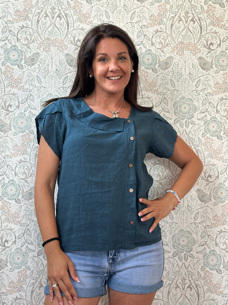 Camicia a manica corta con scollo a barchetta, colletto laterale e dettaglio linea con bottoni decorativi. 
