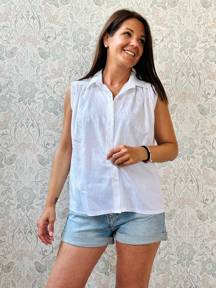 Camicia bianca senza maniche con colletto e pinces sul petto. Taglio svasato e vestibilità 