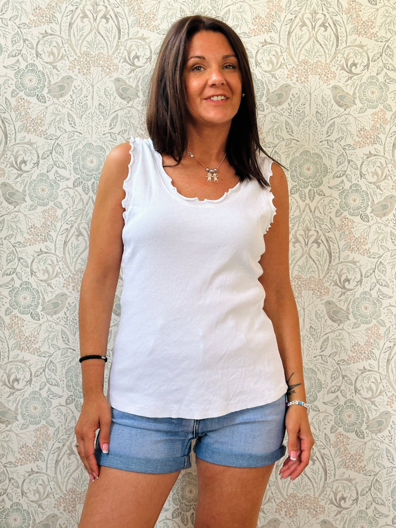 Canotta 100% cotone, scollo tondo con frou frou, tessuto a costine e vestibilità morbida. 