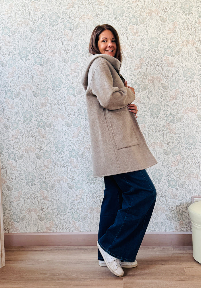 Cappotto beige, taglio dritto e ampio con chiusura zip, cappuccio e tasche sul davanti a viste e aperte. 