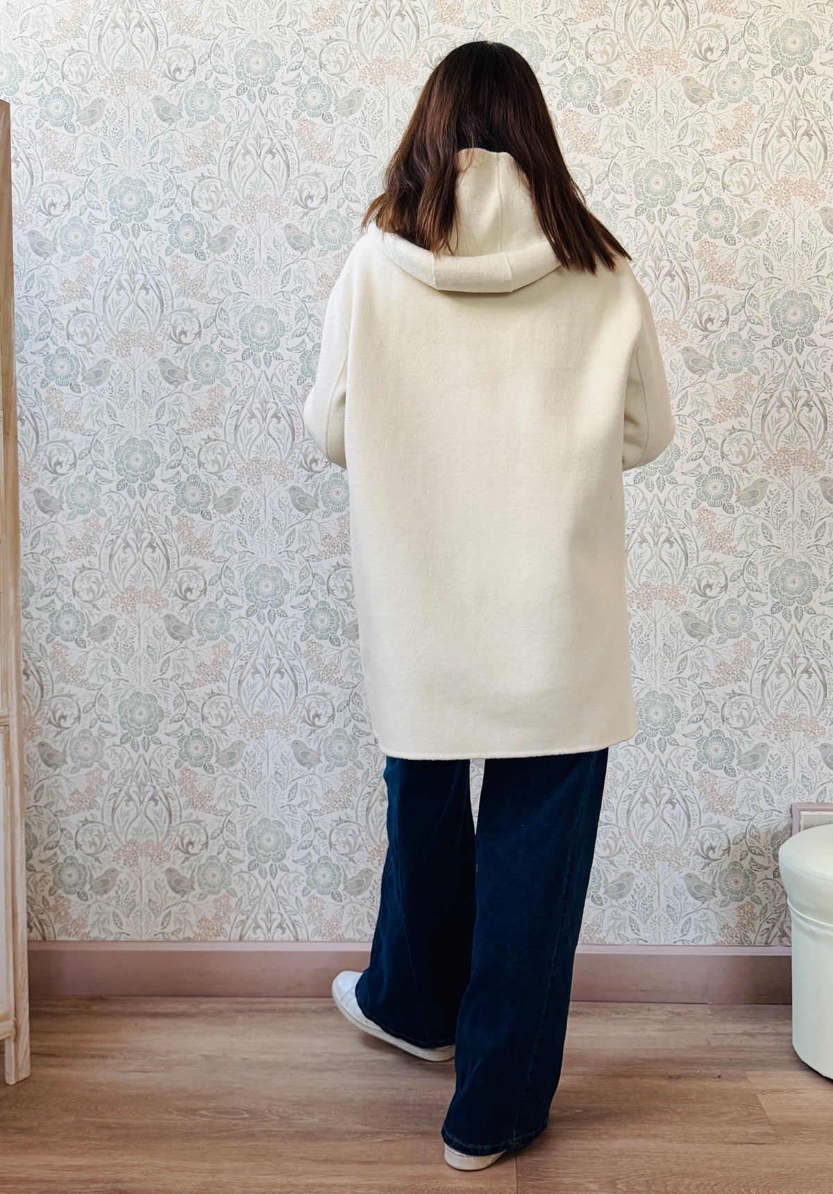 Cappotto color panna, taglio dritto e ampio con chiusura zip, cappuccio e tasche sul davanti a viste e aperte.  
