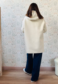 Cappotto color panna, taglio dritto e ampio con chiusura zip, cappuccio e tasche sul davanti a viste e aperte.  