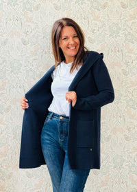 Cardigan da donna lungo con cappuccio e tasche a vista aperte sul davanti. 