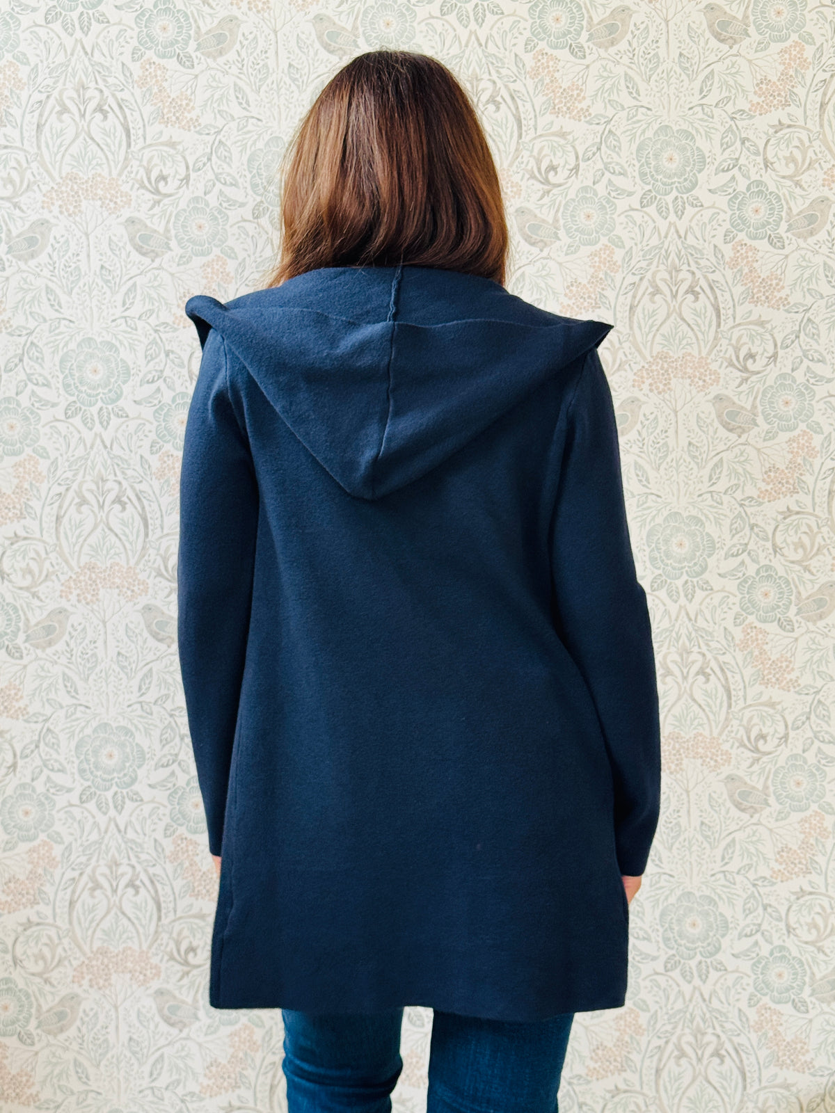 Cardigan da donna lungo con cappuccio e tasche a vista aperte sul davanti. 