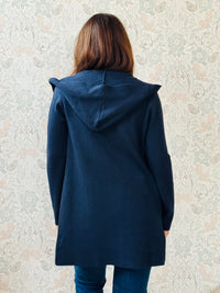 Cardigan da donna lungo con cappuccio e tasche a vista aperte sul davanti. 
