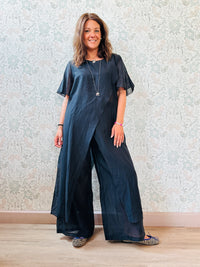 Completo composto da: pantaloni a palazzo con elastico in vita e pantaloncini interno + blusa lunga a manica corta, scollo tondo e taglio a portafoglio