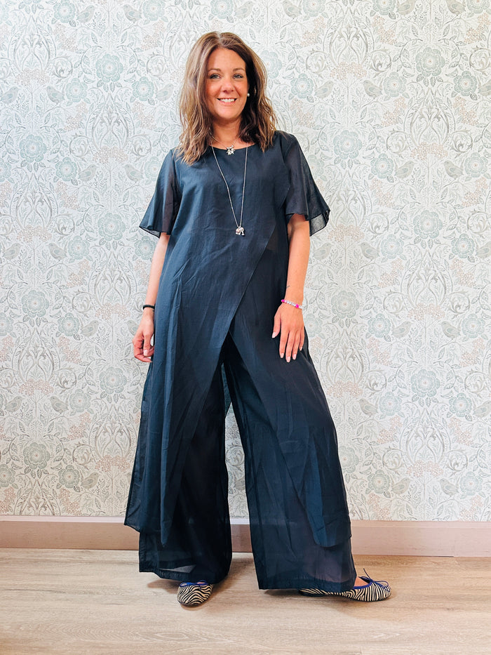 Completo composto da: pantaloni a palazzo con elastico in vita e pantaloncini interno + blusa lunga a manica corta, scollo tondo e taglio a portafoglio
