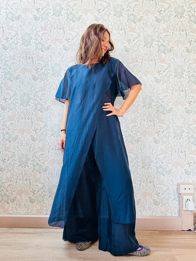 Completo composto da: pantaloni a palazzo con elastico in vita e pantaloncini interno + blusa lunga a manica corta, scollo tondo e taglio a portafoglio