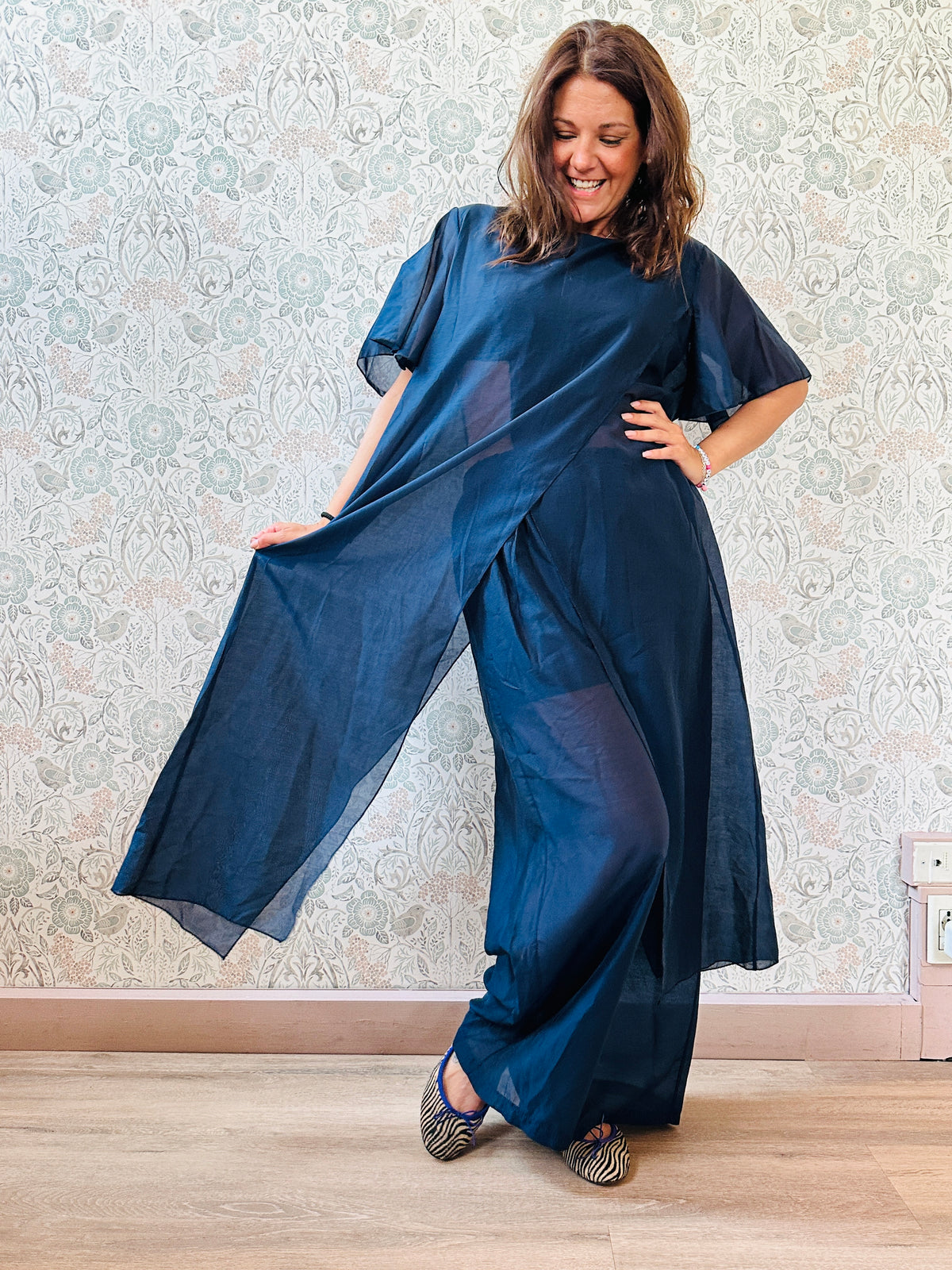 Completo composto da: pantaloni a palazzo con elastico in vita e pantaloncini interno + blusa lunga a manica corta, scollo tondo e taglio a portafoglio