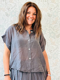 Completo marrone composto da: gonna con balza finale, taglio portafoglio asimmetrico e camicia a manica corta.