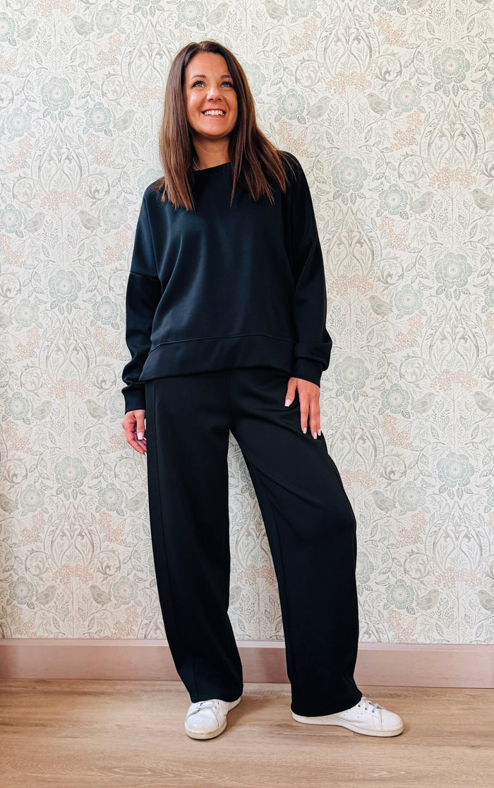 Completo composto da: Pantaloni con elastico in vita, taglio baggy e tasche sui fianchi. Felpa con scollo tondo ampia, svasata e con spacchetti laterali. 
