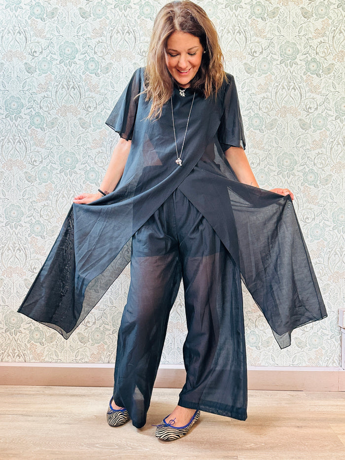 Completo composto da: pantaloni a palazzo con elastico in vita e pantaloncini interno + blusa lunga a manica corta, scollo tondo e taglio a portafoglio