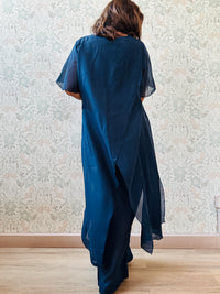 Completo composto da: pantaloni a palazzo con elastico in vita e pantaloncini interno + blusa lunga a manica corta, scollo tondo e taglio a portafoglio