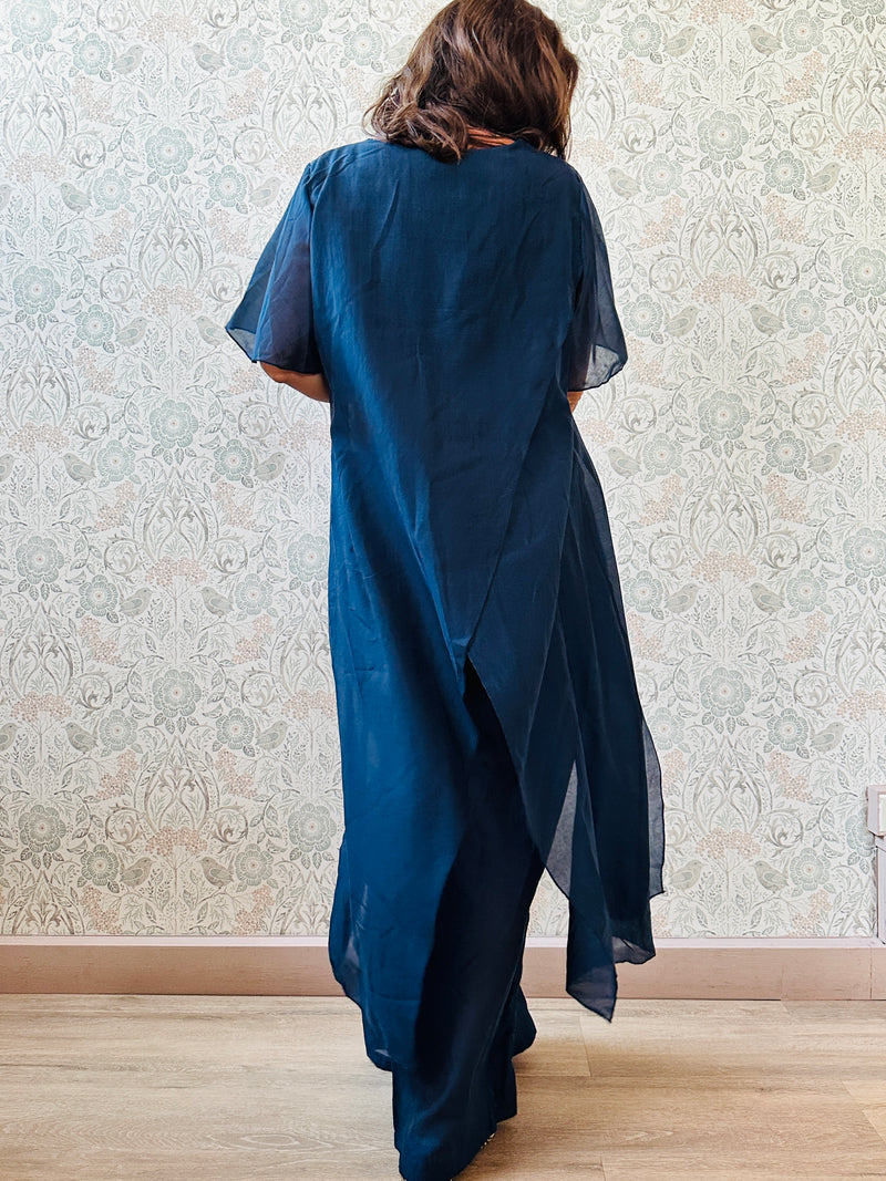 Completo composto da: pantaloni a palazzo con elastico in vita e pantaloncini interno + blusa lunga a manica corta, scollo tondo e taglio a portafoglio