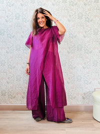 Completo composto da: pantaloni a palazzo con elastico in vita e pantaloncini interno + blusa lunga a manica corta, scollo tondo e taglio a portafoglio
