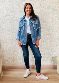 Giacca jeans in tessuto denim dal taglio dritto e molto ampio, tasche a vista aperte sul davanti con applicazioni e dettagli sfrangiati. 