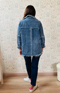 Giacca jeans in tessuto denim dal taglio dritto e molto ampio, tasche a vista aperte sul davanti con applicazioni e dettagli sfrangiati.  