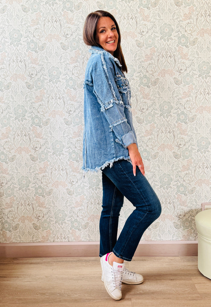 Giacca jeans in tessuto denim dal taglio dritto e molto ampio, tasche a vista aperte sul davanti con applicazioni e dettagli sfrangiati. 