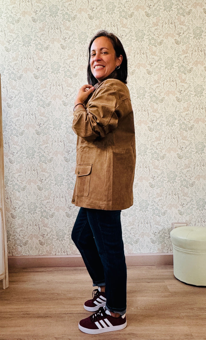 Giacca scamosciata con colletto, chiusura con zip coperta e tasche laterali aperte con chiusura con bottone. 