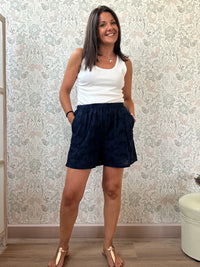 Pantaloncini 100% cotone con elastico in vita, tasche laterali e ricami sangallo. 