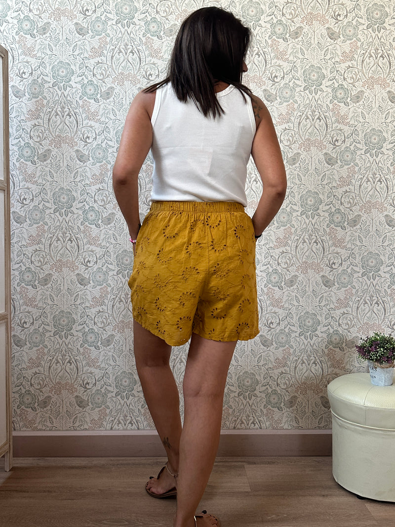 Pantaloncini 100% cotone con elastico in vita, tasche laterali e ricami sangallo. 