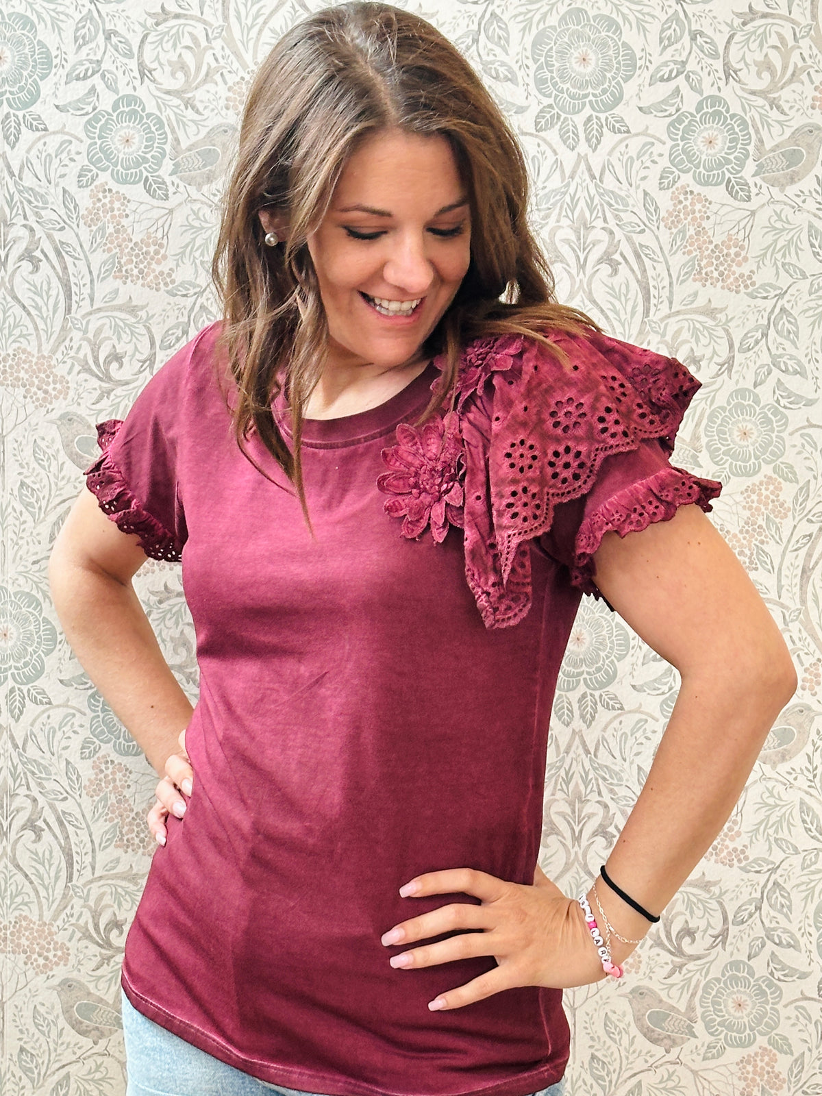 T-shirt bordeaux a manica corta con dettaglio volant e sangallo. Scollo tondo, taglio dritto e leggermente svasato.