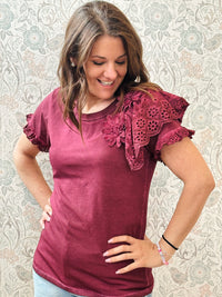 T-shirt bordeaux a manica corta con dettaglio volant e sangallo. Scollo tondo, taglio dritto e leggermente svasato.