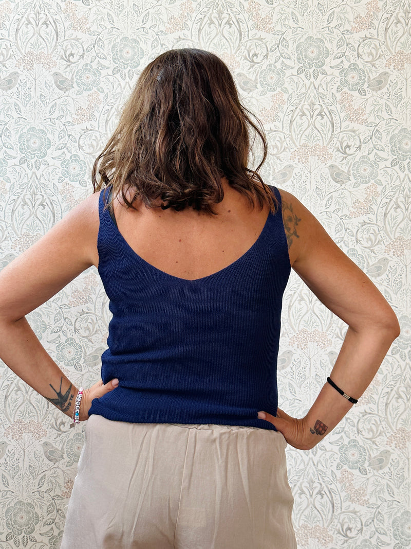 Top con scollo a V fronte e retro. Trama a costine e taglio dritto ed aderente.
