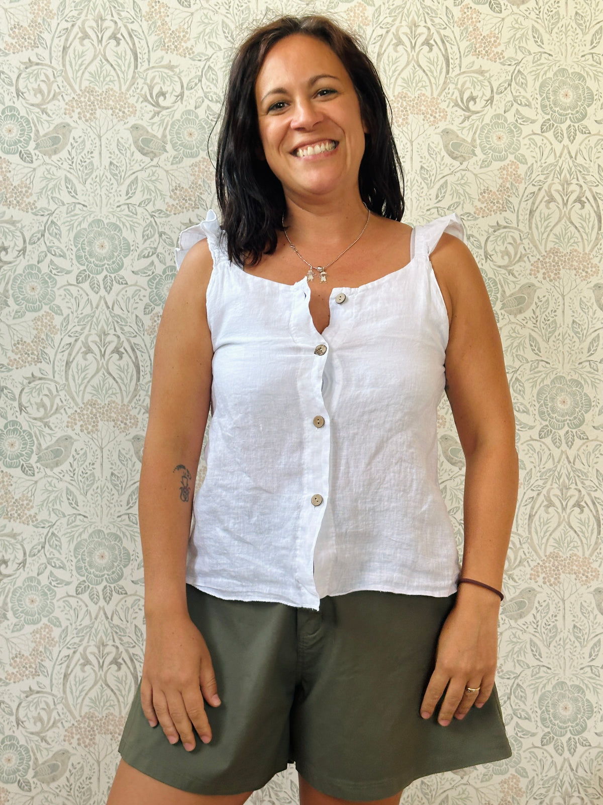 Top 100% lino, con spalline frou frou, leggermente svasato e chiusura con bottoni. 